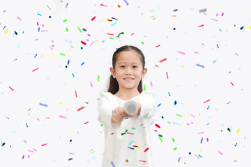 Happy little Asian child girl shooting party popper confetti over white background.