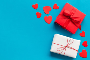 Present to a lover on Valentine's Day. Gift boxes near paper hearts on blue background top-down frame copy space