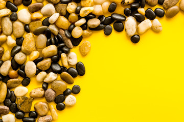 Summer trip to sea concept. Stones on yellow background top-down frame copy space