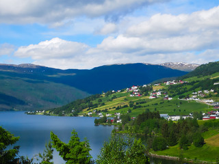 Fototapeta na wymiar A beautiful Norwegian mountain landscape with fjord and farms in spring with blue sky and clouds.