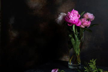 A bouquet of pink peonies stands on a dark background. Creative picture for Wallpaper and interior.