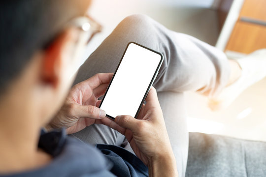 Mockup image blank white screen cell phone.men hand holding texting using mobile on sofa at home office.background empty space for advertise text.people contact marketing business and technology 