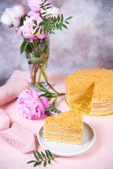 Delicious cake honey cake is on the table with flowers.