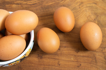 There are many fresh eggs in the picture, placed in cups and on wooden floors.