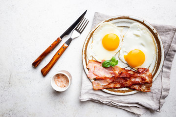 Fried eggs and bacon for breakfast on a plate, top view, copyspace