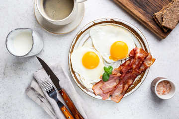 Fried eggs and bacon for breakfast on a plate, top view, copyspace