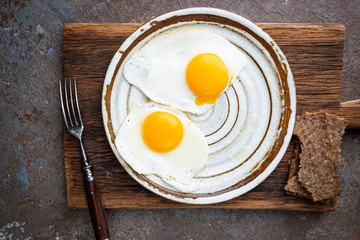 Fried eggs for breakfast on a plate, top view, copyspace