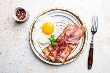 Fried eggs and bacon for breakfast on a plate, top view, copyspace