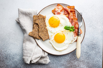 Fried eggs and bacon for breakfast on a plate, top view, copyspace