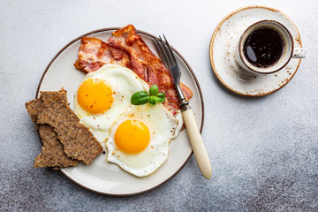 Fried eggs and bacon for breakfast on a plate, top view, copyspace