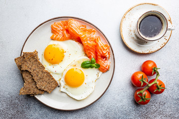 Top view of healthy breakfast with fried eggs and smoked salmon in a plate