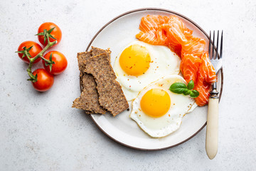 Top view of healthy breakfast with fried eggs and smoked salmon in a plate