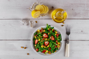 Green salad with arugula, strawberries and mango with olive oil and lemon.