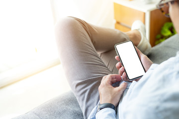 Mockup image blank white screen cell phone.men hand holding texting using mobile on desk at home office.background empty space for advertise text.people contact marketing business,technology 