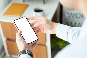 Mockup image blank white screen cell phone.men hand holding texting using mobile on desk at home office.background empty space for advertise text.people contact marketing business,technology 