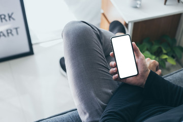 Mockup image blank white screen cell phone.men hand holding texting using mobile on desk at home office.background empty space for advertise text.people contact marketing business,technology 
