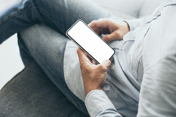 Mockup image blank white screen cell phone.men hand holding texting using mobile on desk at home office.background empty space for advertise text.people contact marketing business,technology 