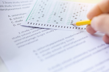 Obraz premium high school,university student study.hands holding pencil writing paper answer sheet.sitting lecture chair taking final exam attending in examination classroom.concept scholarship for education abroad