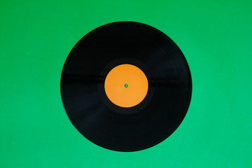 Vinyl record on a green background. Retro style. Top view.