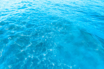 Blue transparent sea water near the beach texture background. clear water surface with slight waves and glare on a sunny day. sea ​​vacation