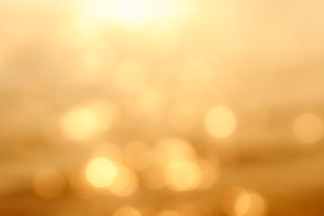 Delicate golden texture bokeh background. blurry yellow bokeh glare on the water during sunset and dawn