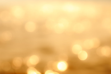 Delicate golden texture bokeh background. blurry yellow bokeh glare on the water during sunset and...