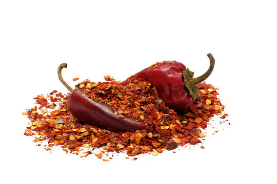 heap of ground dried chili pepper flakes and pods isolated on white background, full depth of field