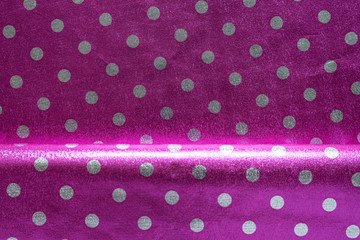 Purple shiny wrapping paper with polka dots with a fold. Foil for the design of gift wrapping, wallpaper. Stylish shiny texture