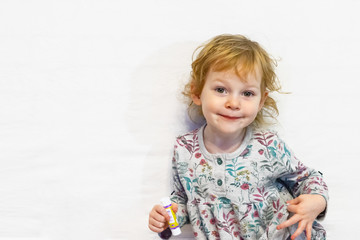 Fototapeta premium Little girl of three years old, looking at the camera and smiling.Defocused image.