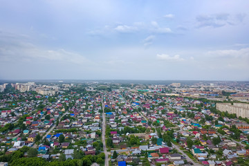Obraz premium Aerial view of a large number of small houses with colored roofs on the outskirts of novosibirsk on an summer sunny day with the road and cars