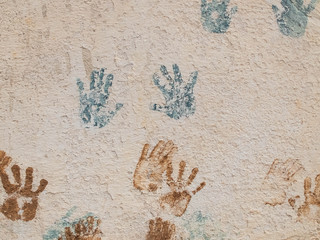 Blue and brown paint palm prints on the textured plaster