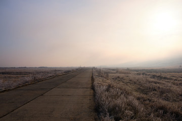 Remote road in a foggy late autumn morning
