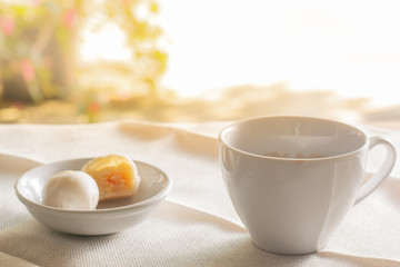 side view white cup of hot coffee served with two small mooncake on table with vintage tone. Break times concept.