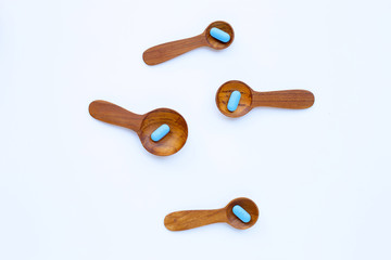 Medical blue pills with wooden spoon on white