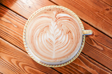 A Cup of hot latte art coffee on wooden table