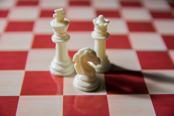 Top shot of three close up chess pieces. King, queen and knight on chess board