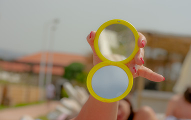 Female hand holding a yellow pocket mirror