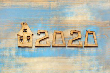 Wooden plaques form the number two thousand twenty, next to the model of the house top view. new...