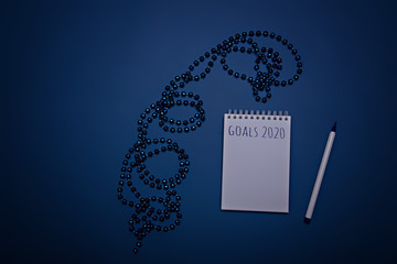 Blue Christmas beads, notebook and pen on a blue background. Color of the year 2020, Classic Blue