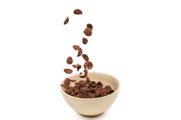 Chocolate corn flakes falling to the white bowl isolated on white. Motion.