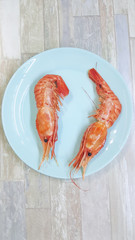 Fresh and tasty boiled wild king prawns with on plate ready for eating. Big red shrimps.