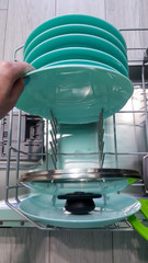 woman's hand holds clean dishes after washing in the dishwasher.