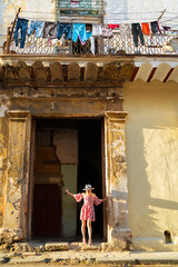 Young woman in a colored dress leaves a dilapidated house