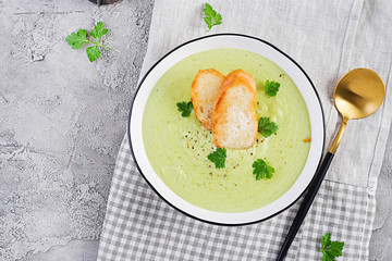 Homemade broccoli cream soup with croutons in white bowl on grey background. Healthy vegetarian food. Vegan menu. Top view, copy space