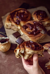 Brioche with chocolate in hand close-up on a background of other buns