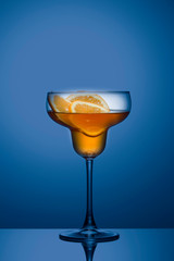 Summer refreshing faintly alcoholic cocktail with orange on a blue gradient background