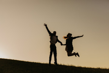 Happy young couple enjoying outdoors during sunset .