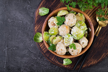 Brussels sprouts roasted with chicken meatballs and onions in a creamy sauce. Top view