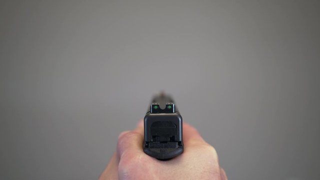 Close up of handgun sights aiming at blank background with focus pull