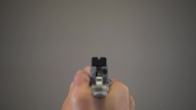 Silver handgun cocked, aimed and dry fired at blank background